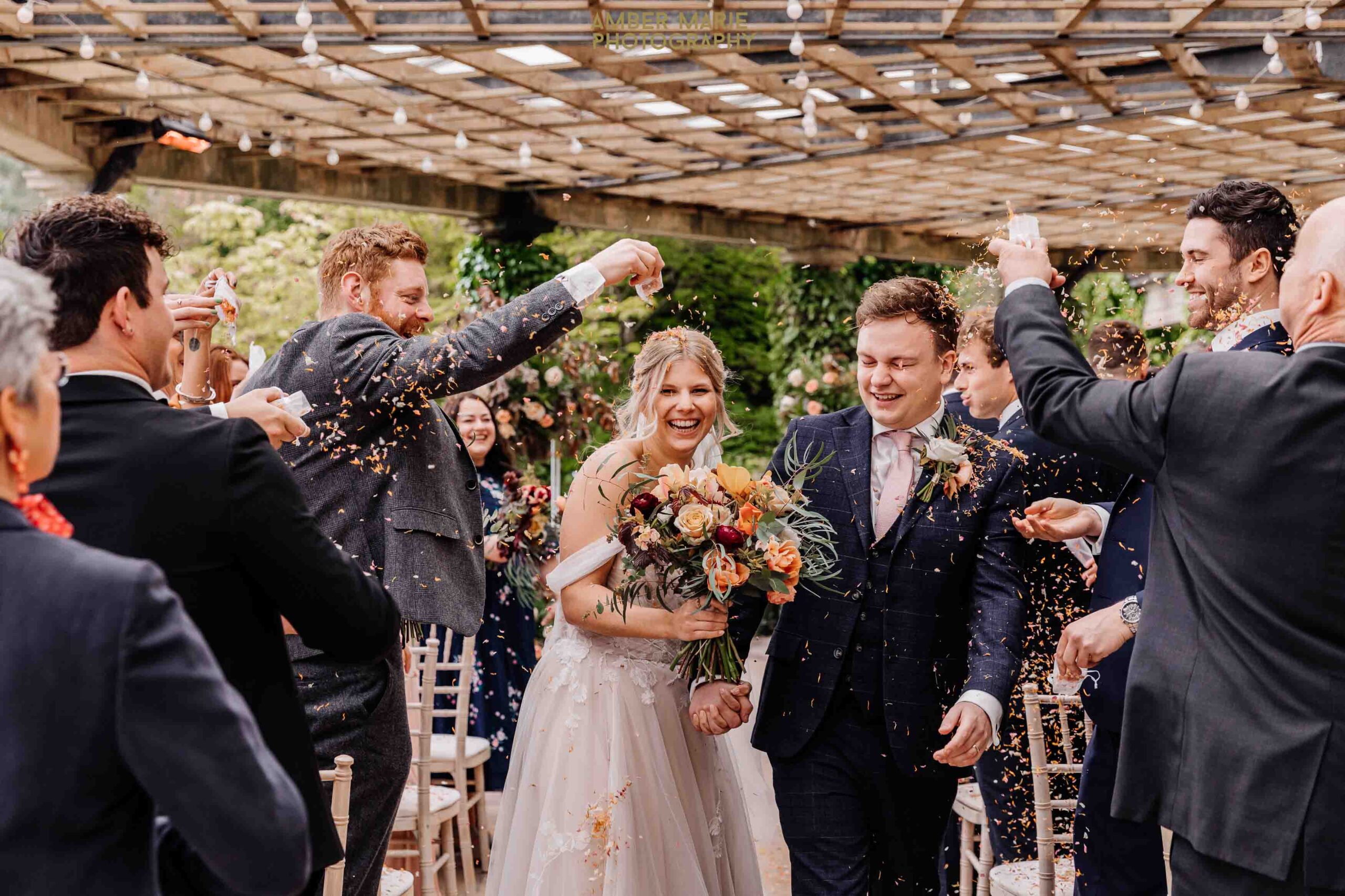creative wedding photography of bride and groom exiting ceremony whilst guests throw confetti